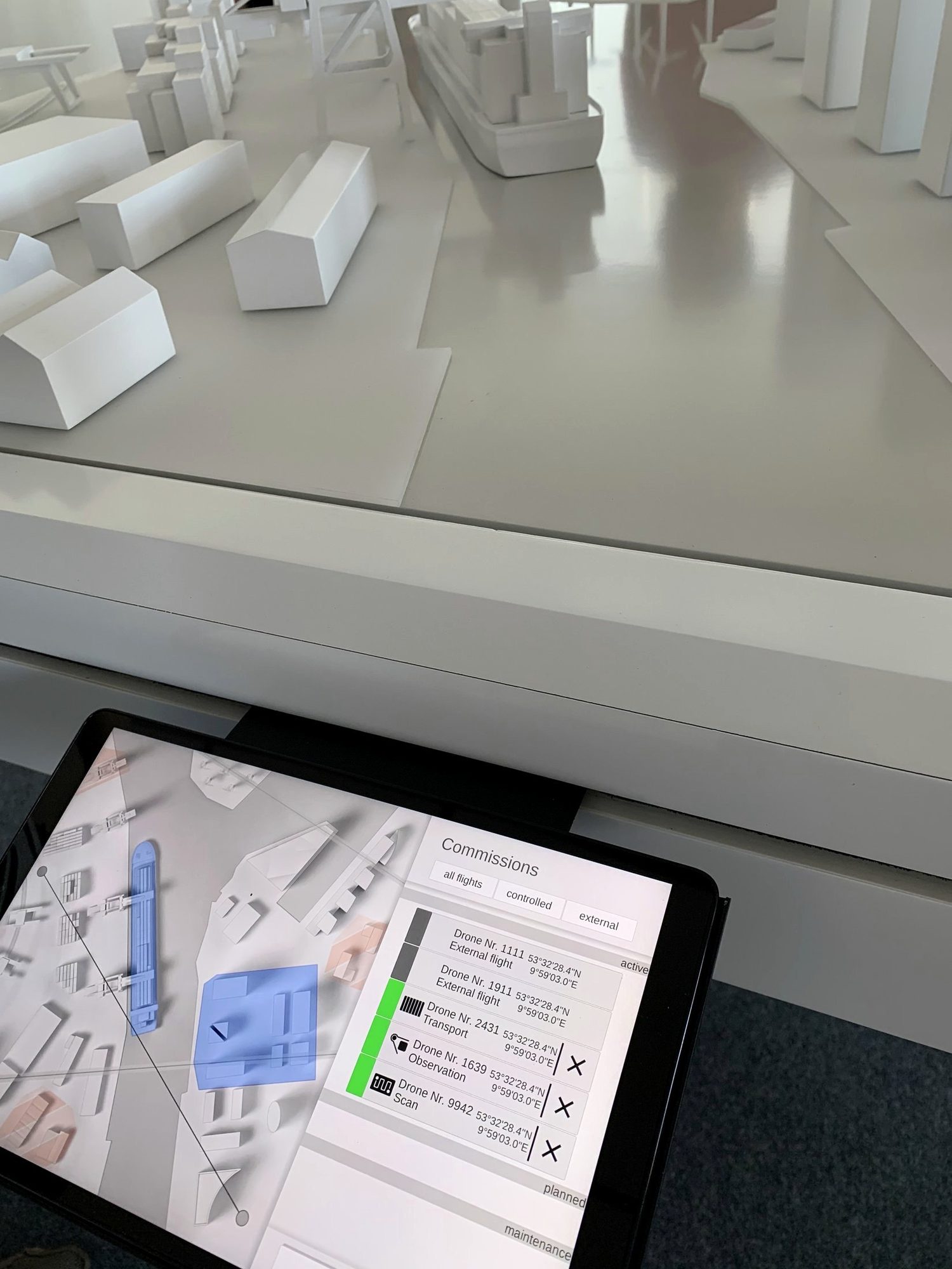 Tablet mit Flugübersicht vor dem Modell
